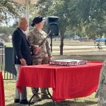 John Burnam cuts the commemorative cake to mark the conclusion of the event. A sword is used to cut the first slice.