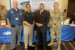 Three members of the AHF Board plus a member of the Airman Heritage Museum staff take a photo in front of display.